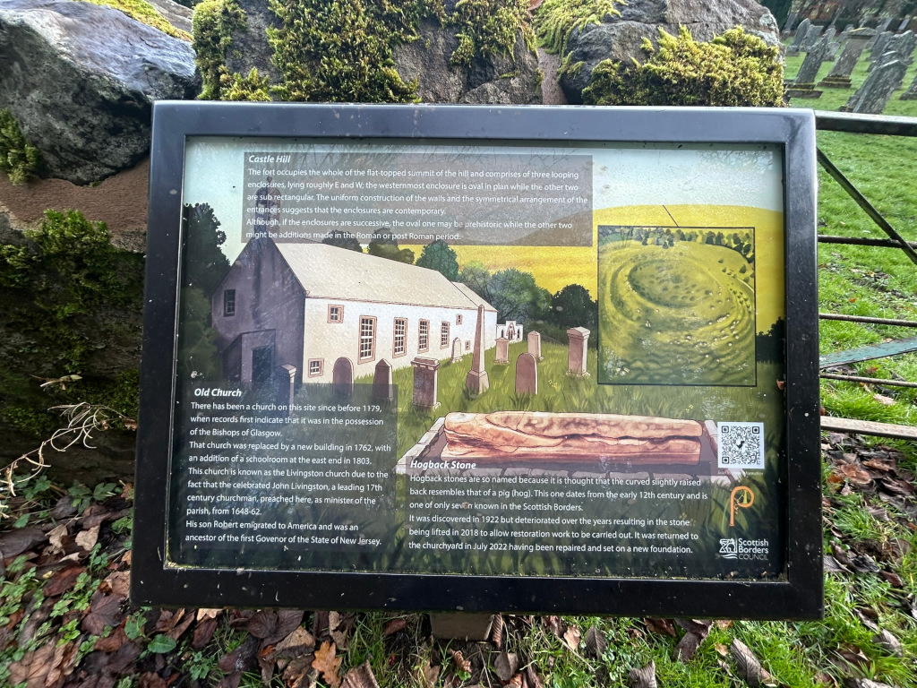 Weathered information board located outdoors, likely in a historical site. The board provides details about three historical features: Castle Hill (a fort with three enclosures), Old Church (with its history and notable connections), and Hogback Stone (a unique, historically significant stone). The board includes illustrations of the fort, church, and stone, along with text explaining their significance and historical context. The style suggests a historical or archaeological site, potentially in Scotland. The overall message is informative and educational, aiming to provide visitors with a brief history of the location.