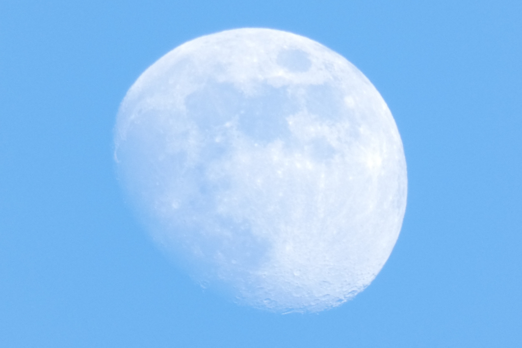Moon dominates the frame, occupying a significant portion of the image's area. It's positioned slightly off-center, leaning towards the left side. The moon appears luminous, with a soft, white light that is not harsh or overly bright. Its surface is textured with subtle craters and shadows, lending a three-dimensional quality to its appearance.