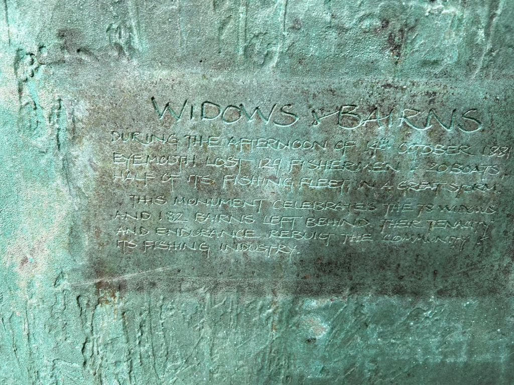 Weathered bronze plaque, seemingly a monument or memorial. The text on the plaque commemorates the loss of 124 fishermen and 20 boats in Eyemouth, Scotland, during a great storm on October 14th, 1881. This event resulted in 78 widows and 182 children (bairns). The monument celebrates the tenacity and endurance of the community in rebuilding itself and its fishing industry after this devastating tragedy. The texture of the bronze and the slightly worn inscription contribute to the sombre and historical tone of the piece.