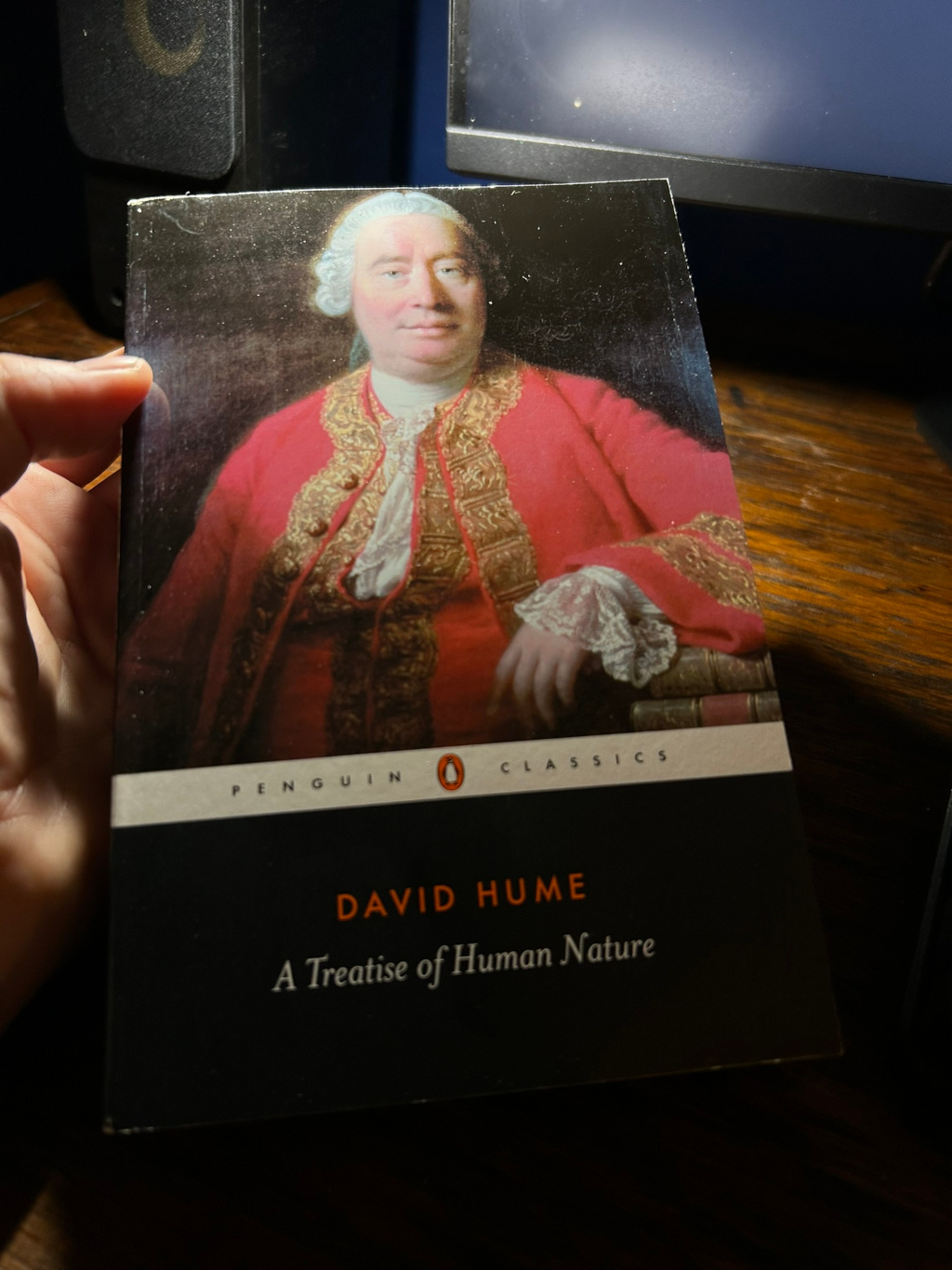 Penguin Classics edition of David Hume's A Treatise of Human Nature. The cover features a portrait of Hume, dressed in 18th-century attire. The book is being held in Leonie's hand.
