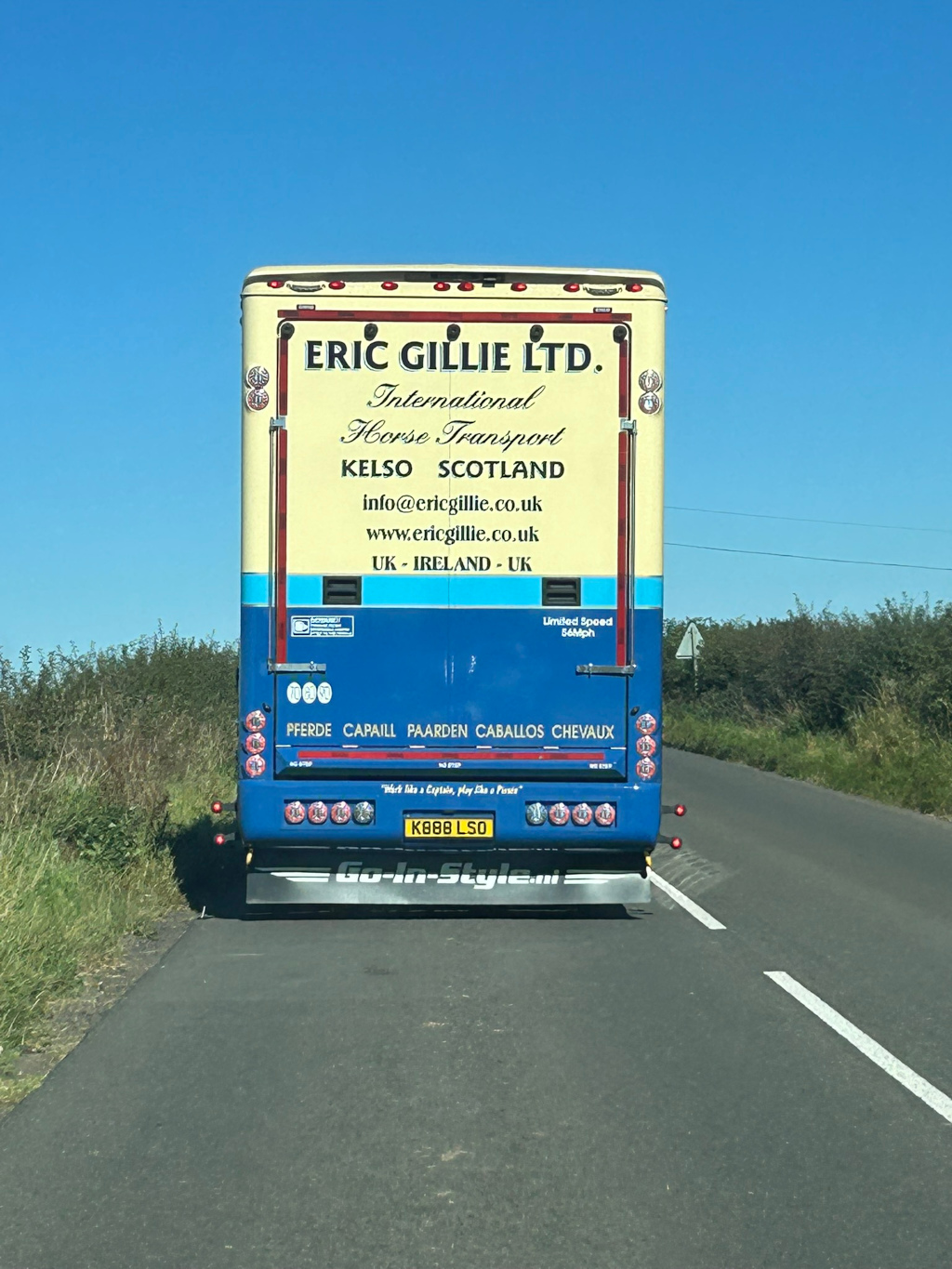 Rear of a horse transport truck belonging to Eric Gillie Ltd, based in Kelso, Scotland. The truck's livery is a striking combination of cream and blue, clearly displaying the company's name, services (International Horse Transport), contact information, and operating areas (UK and Ireland).