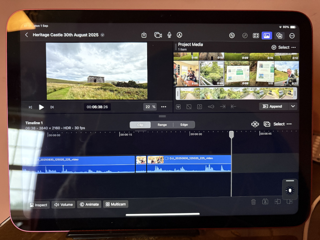Tablet displaying a video editing interface. The main focus is a video clip of a stone structure, possibly a ruin or small castle, set against a landscape. The editing software is showing thumbnails of other video clips and audio waveforms, suggesting a project in progress documenting a visit to a heritage castle on August 30th, 2025. The overall impression is one of digital media creation and preservation of a historical site visit.