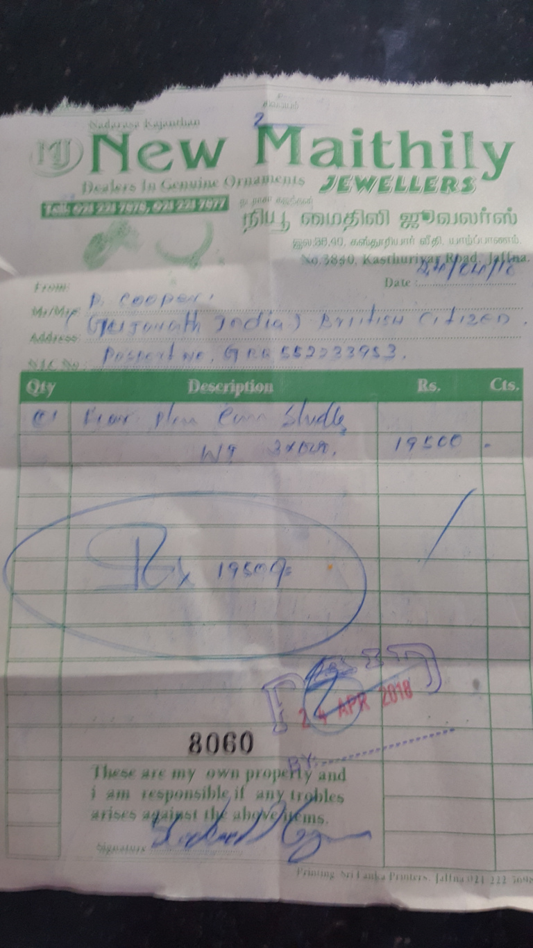 faded, slightly crumpled receipt from a jewellery store, New Maithily Jewellers, predominantly in green text against a white background. The receipt is the central focus, taking up most of the frame. It's a handwritten and stamped document, showing details of a purchase. The handwriting varies in style and legibility. The top shows the store's name and contact information, including phone numbers and an address in Tamil script. The customer's information is filled out at the top.